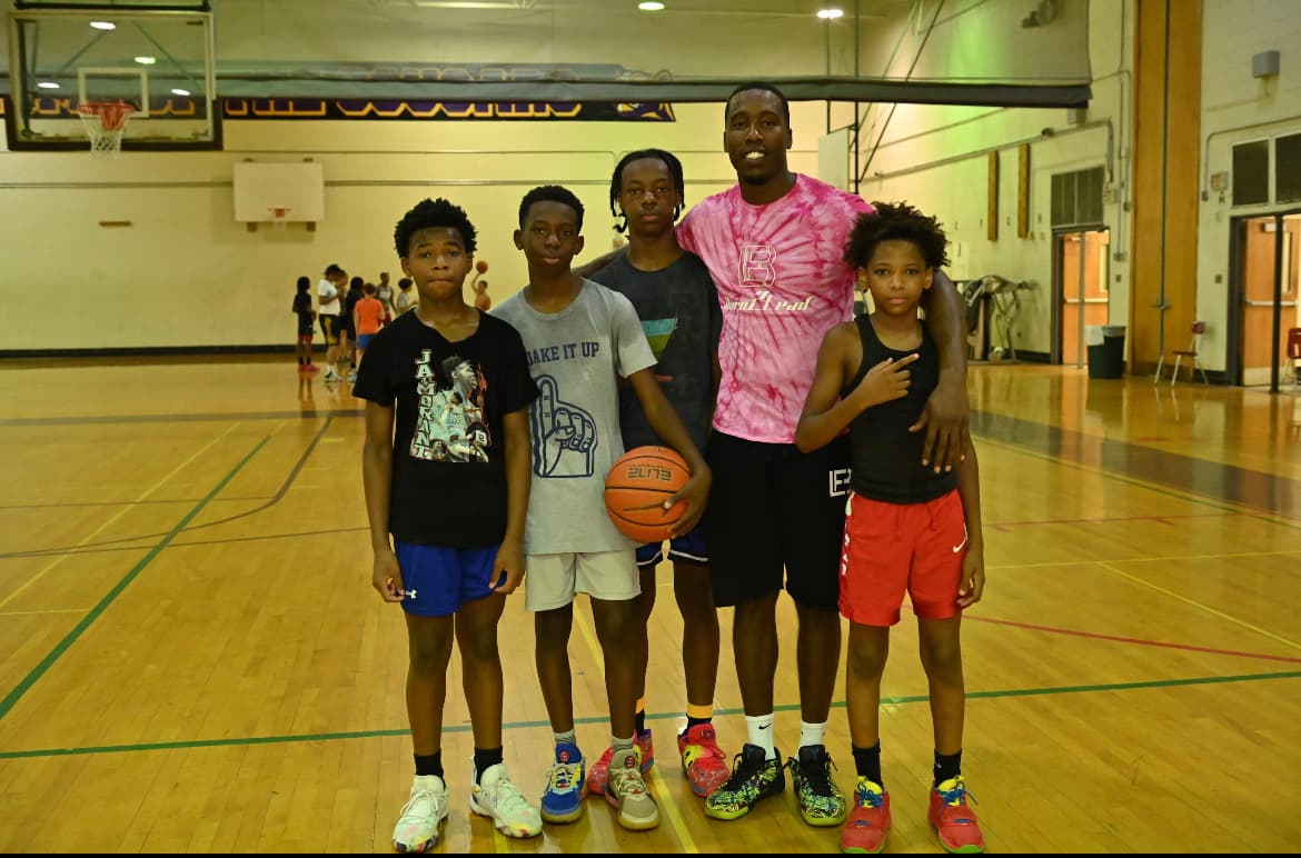 Tasheed Carr in BLF pink tie-dye with four young athletes at basketball camp