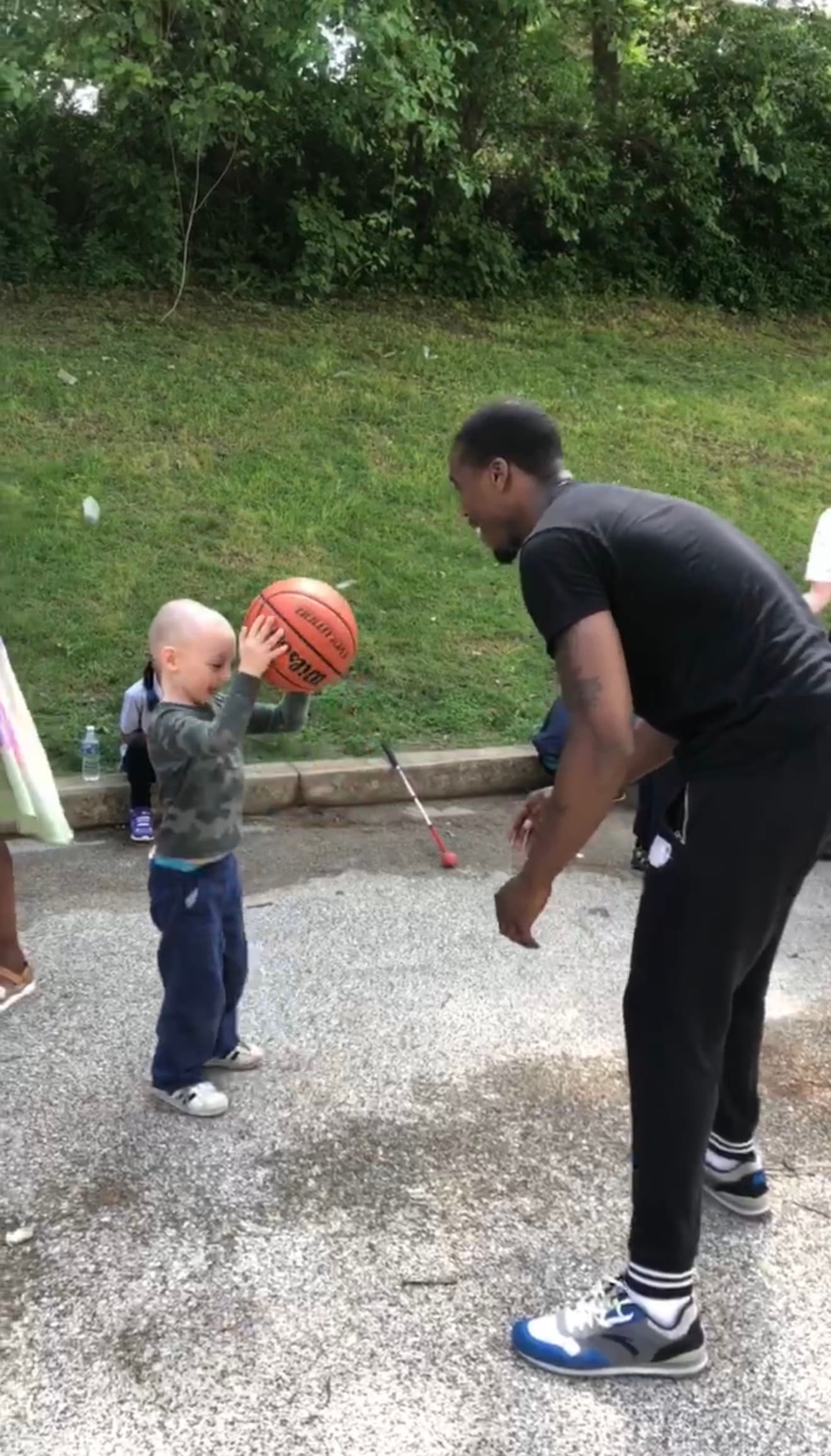 Tasheed Carr playing basketball with a young child at a special needs event