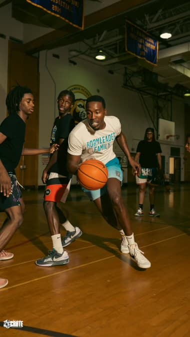 Tasheed Carr driving to the basket in a Born Leader Family shirt during a game